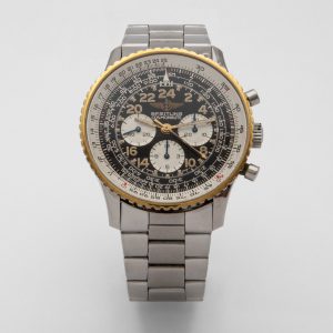 Un rellotge de polsera Breitling amb una corretja de metall platejat i un detallat esfera en blanc i negre amb diversos retoladors, una vora amb vores daurades i tres esferes més petites per obtenir informació addicional. Joieria Vintage Barcelona