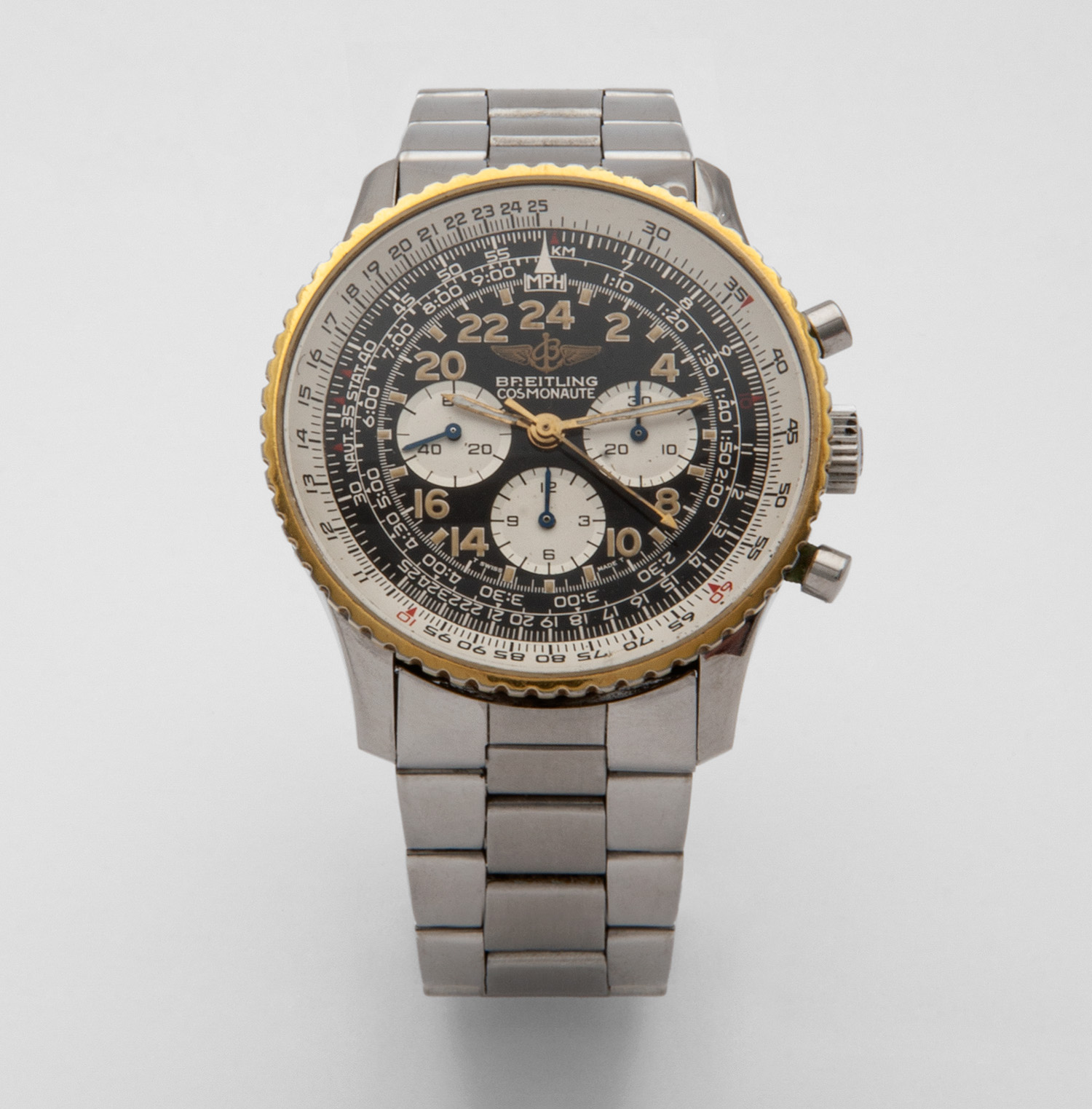 Un rellotge de polsera Breitling amb una corretja de metall platejat i un detallat esfera en blanc i negre amb diversos retoladors, una vora amb vores daurades i tres esferes més petites per obtenir informació addicional. Joieria Vintage Barcelona