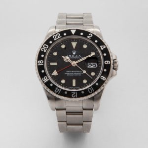 Reloj de pulsera con correa de metal plateada, bisel y esfera negros. El reloj incluye marcadores de hora blancos, dos manecillas horarias y una lupa de fecha en el lado derecho. El nombre de la marca "Breitling Navitimer Cosmonaute" es visible en la esfera. Joieria Vintage Barcelona