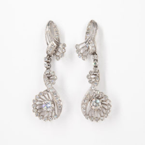 Pendientes oro blanco 18K y diamantes que presentan un diseño de remolino con diamantes brillantes y un diamante central prominente en un engaste circular, que se muestra sobre un fondo blanco. Joieria Vintage Barcelona