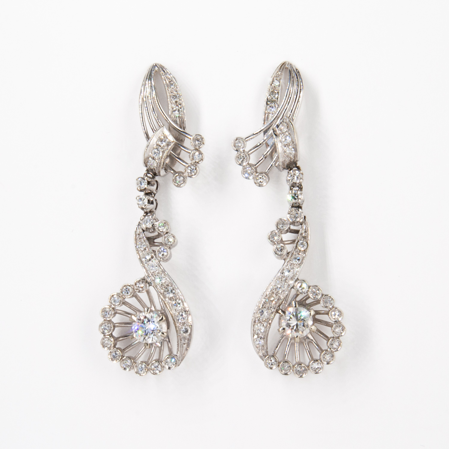 Pendientes oro blanco 18K y diamantes que presentan un diseño de remolino con diamantes brillantes y un diamante central prominente en un engaste circular, que se muestra sobre un fondo blanco. Joieria Vintage Barcelona