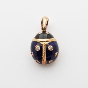 A Yanes pendant crafted from 18 kt yellow gold, featuring a ladybug design with intricate enamel detailing. The body is adorned in dark blue with sparkling diamond spots and a black head. It includes a loop for attaching to a chain and is set against a plain white background. Joieria Vintage Barcelona