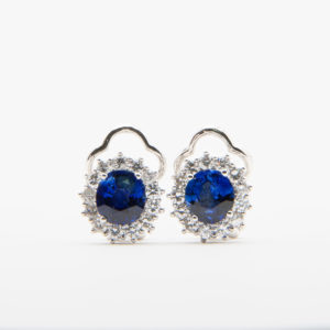 Presentamos los "Pendientes de oro blanco de 18K con zafiros y diamantes", unos exquisitos pendientes elaborados en oro blanco que muestran zafiros de un azul profundo elegantemente rodeados de brillantes diamantes. Estos pendientes presentan un sofisticado diseño festoneado en la parte superior y se presentan de forma hermosa sobre un fondo blanco liso. Joieria Vintage Barcelona