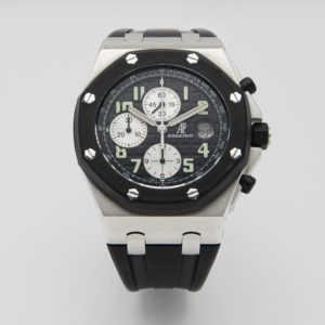 L'Audemars Piguet Royal Oak Offshore és un rellotge de polsera de luxe amb un impressionant disseny negre i plata. Compta amb un taquímetre visible, tres subesferes i marcadors d'hora numerats en negreta. Aquest rellotge elegant està equipat amb una corretja de goma negra i detalls metàl·lics a la caixa. Joieria Vintage Barcelona