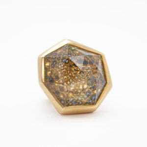 Presentamos el Anillo Vasari en oro amarillo de 18 quilates, que presenta un diseño geométrico con una piedra citrina facetada que encierra partículas brillantes de diamantes, zafiros y granates para una apariencia moderna y lujosa. El anillo se presenta elegantemente sobre un fondo blanco. Joieria Vintage Barcelona
