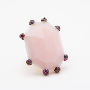 A large, faceted octagonal pink opaline gemstone is set in an 18K rose gold ring, secured by multiple decorative red and gold prongs. The background is plain white. Joieria Vintage Barcelona