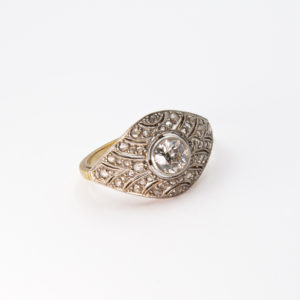 L'"Anell Belle Epoque d'or groc 18K, platí i diamants" és un anell ornamentat d'estil vintage amb un diamant rodó central envoltat d'intricats detalls de filigrana en una banda d'or, molt ben presentat sobre un fons blanc. Joieria Vintage Barcelona