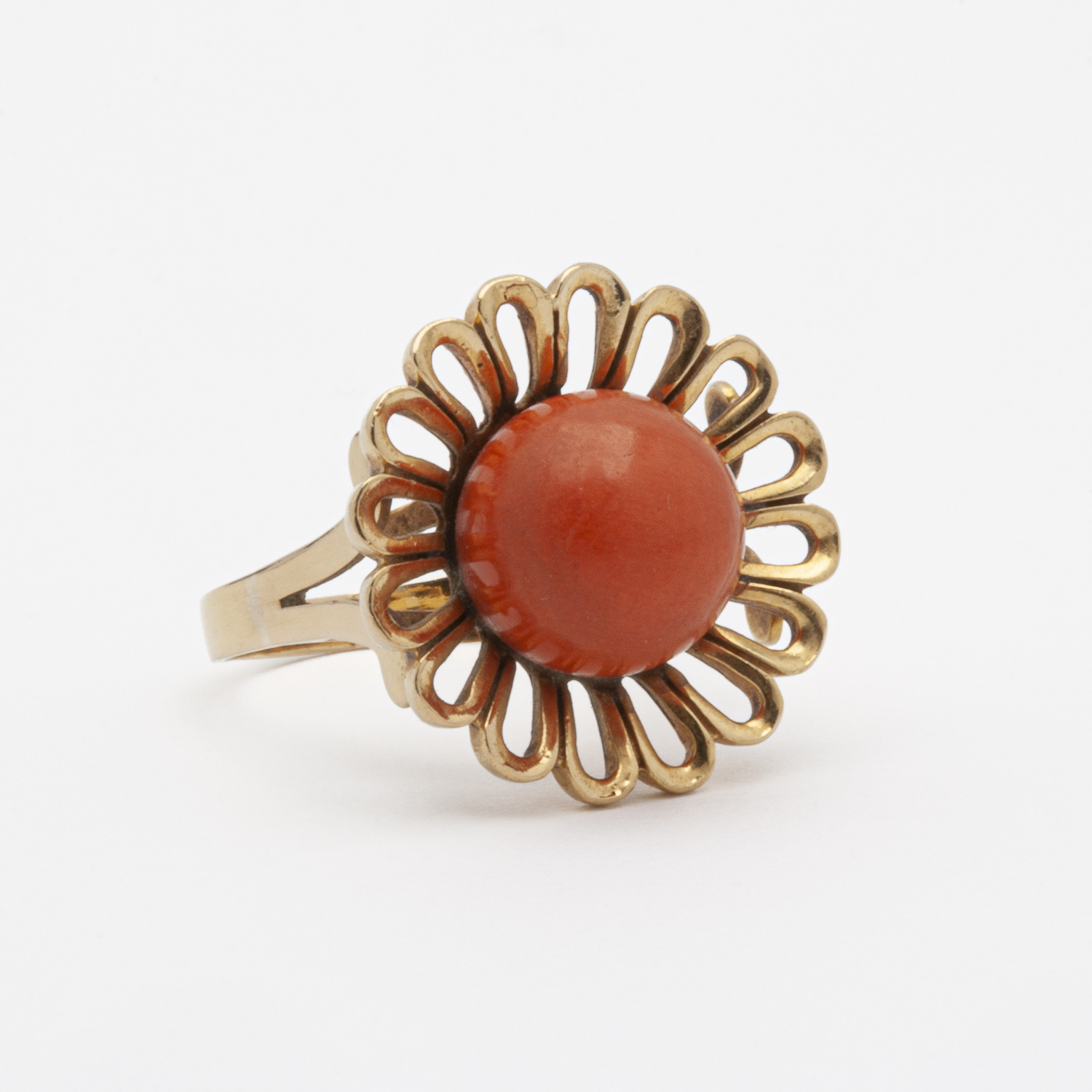 El anillo de oro amarillo de 18 quilates y coral presenta una piedra coral grande y redonda en el centro, rodeada de un diseño intrincado en forma de pétalo. Su apariencia elegante y vintage se destaca sobre un fondo blanco liso. Joieria Vintage Barcelona
