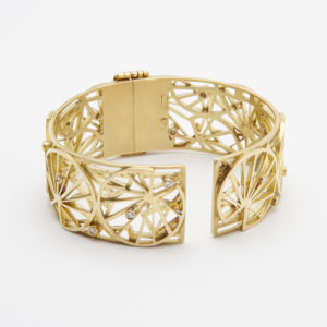 Introducing the 18-karat yellow gold and diamond Bagués bracelet, a gold bracelet with an open lattice design featuring geometric patterns adorned with small diamonds. This exquisite bracelet comes with a hinged clasp and is beautifully presented against a neutral background. Vintage Jewelry Barcelona