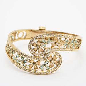 La pulsera Masriera de oro amarillo de 18 quilates presenta un diseño floral detallado, acentuado con pequeños diamantes y esmalte verde claro mediante la técnica "plique-a-jour". Su delicada forma de espiral realza su elegante apariencia. Joieria Vintage Barcelona