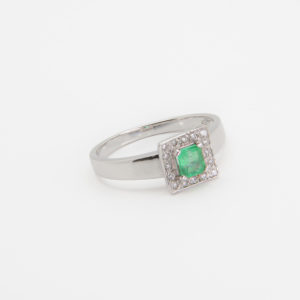 Un anillo de oro blanco de 18 quilates que presenta un cuadrado de corte esmeralda y está rodeado de pequeños diamantes en una banda sencilla, resaltado sobre un fondo blanco. Joieria Vintage Barcelona