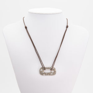 Un collaret exposat sobre un bust blanc, amb un cordó marró i un penjoll ovalat Penjoll Vasari en o amb diamants de 18K incrustat amb pedres petites i brillants. Joieria Vintage Barcelona