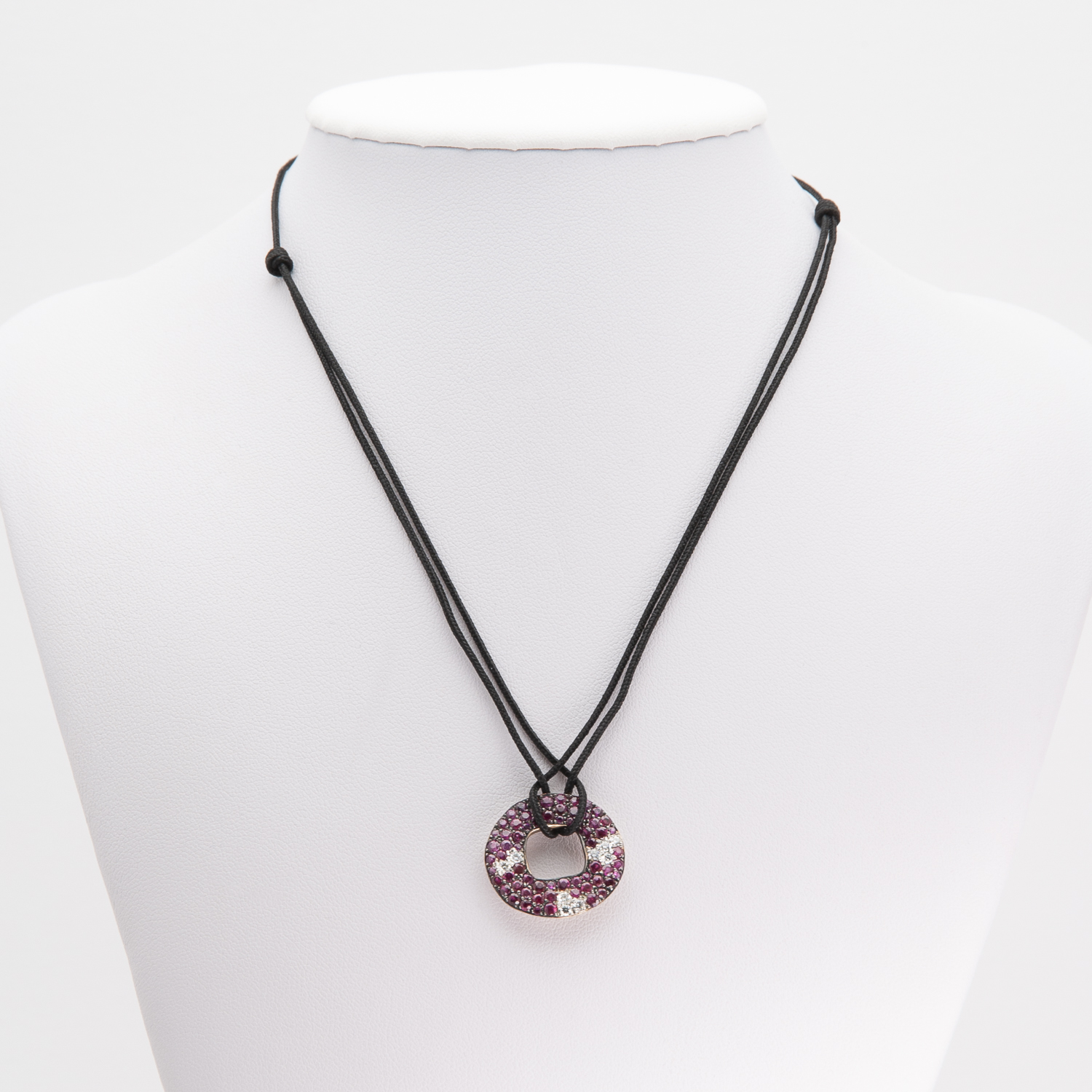 Un collaret de cordó negre exposat en un bust de maniquí blanc, que mostra el Penjoll Vasari d'or groc de 18K amb un penjoll circular rosa brillant, adornat amb petites pedres precioses. Joieria Vintage Barcelona
