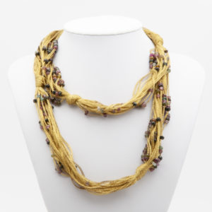 A multi-strand necklace with 18-karat yellow gold threads and vibrant tourmaline beads displayed on a white stand, with the threads intricately twisted together and clusters of beads throughout. Vintage Jewelry Barcelona
