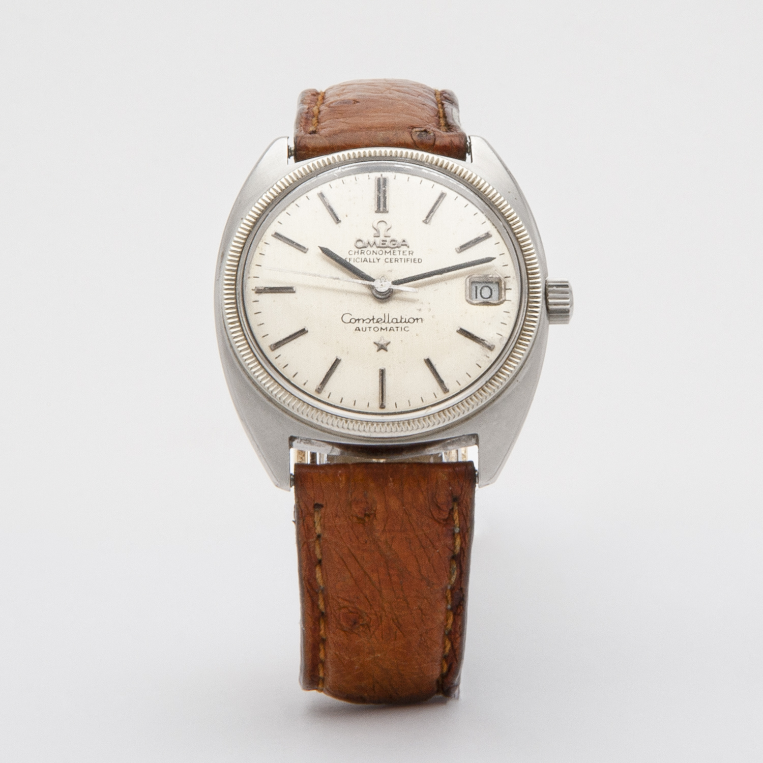 Rellotge Omega Constellation Automàtic d´acer amb corretja de pell marró. L'esfera platejada vintage mostra el logotip de la marca, les paraules "Officially Certified" i "Automatic", juntament amb una finestra de data a la banda dreta de l'esfera. Joieria Vintage Barcelona
