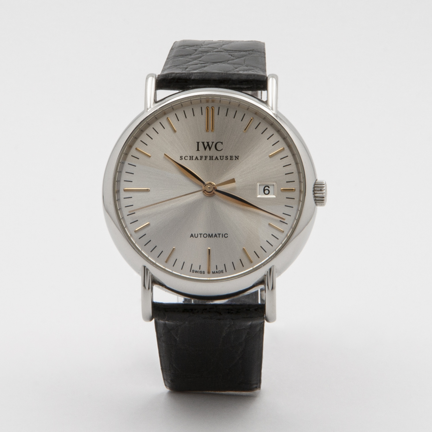 El rellotge de polsera IWC Portofino Acero presenta una caixa platejada elegant, moviment automàtic, esfera blanca, marcadors d'hora daurats, finestra de data a les 3 en punt i una clàssica corretja de cuir negra, bellament presentada sobre un fons llis. Joieria Vintage Barcelona