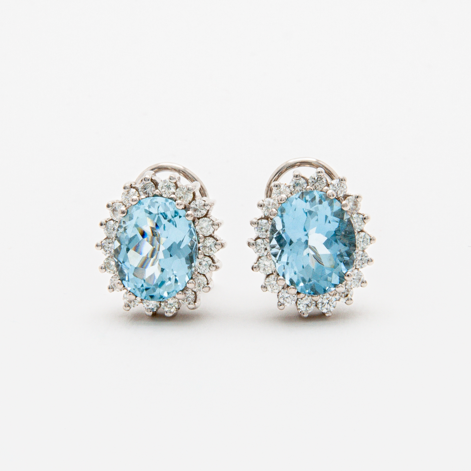 A pair of elegant earrings with large oval aquamarine gemstones surrounded by a halo of sparkling diamonds, set in a silver or white gold metal setting, on a plain white background. Vintage Jewelry Barcelona