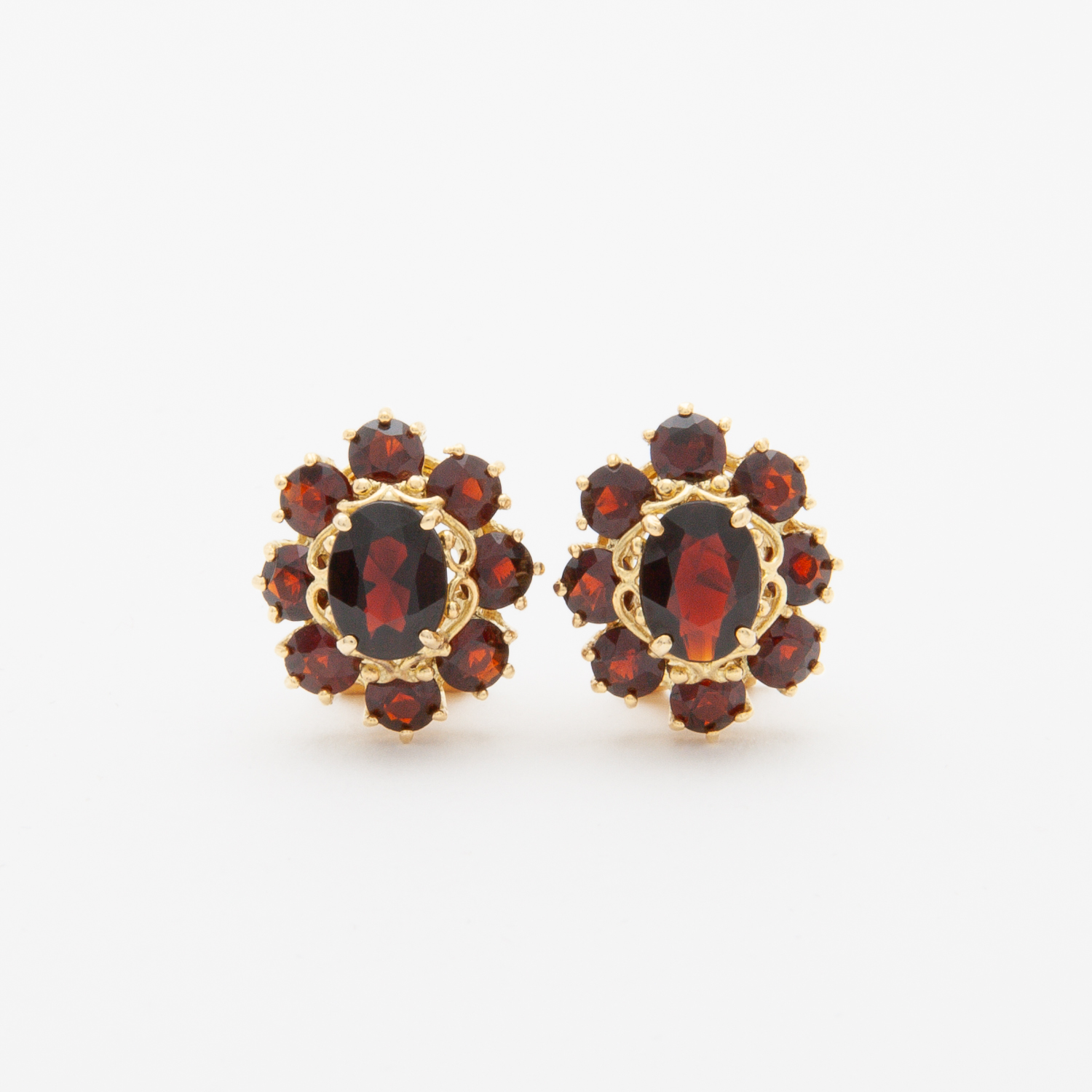 Un par de "Pendientes de granates en oro amarillo 18K" con aretes de oro vintage adornados con piedras preciosas ovaladas de color rojo oscuro y piedras rojas redondas más pequeñas, elaborados en un diseño floral sobre un fondo blanco. Joieria Vintage Barcelona