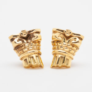 Close-up of Vasari's 18-karat gold "Capitals" earrings, designed like ancient Greek Corinthian columns with intricate details of scrolls and acanthus leaves on a white background. Vintage Jewelry Barcelona