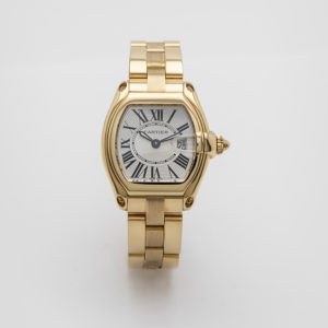 El Cartier Roadster de oro es un elegante reloj de pulsera dorado con correa de metal pulido y esfera rectangular. Cuenta con números romanos, una esfera texturizada con el nombre de la marca, una pequeña ventana de fecha y una corona metálica en el lado derecho que le confiere un aspecto lujoso. Joieria Vintage Barcelona