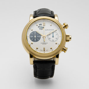 Un rellotge de polsera Graham Chronograph Lightning amb caixa daurada, esfera blanca, corretja de cuir negra, dues subesferes, indicador de data i tres botons laterals està fotografiat sobre un fons blanc llis. Joieria Vintage Barcelona