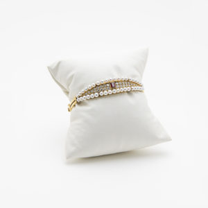 The 18k gold bracelet, with ruby, diamonds and pearls, is elegantly displayed on a padded white pillow against a plain white background. Vintage Jewelry Barcelona