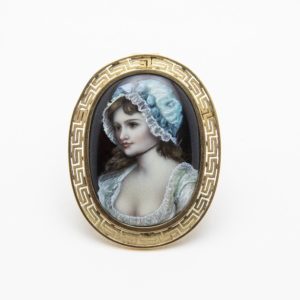 18k gold brooch/pendant with hand-painted fire enamel, featuring a portrait of a young man with a white cap and blue details framed by a gold border with a Greek motif. Vintage Jewelry Barcelona