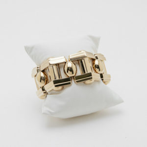 La Pulsera de diseño geométrico en oro de 18k, con formas rectangulares y ovaladas, se muestra sobre un soporte blanco ante un fondo neutro. Joieria Vintage Barcelona
