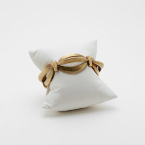 La Pulsera articulada de oro mate de 18k presenta un diseño abstracto ovalado en el centro y se muestra sobre un pequeño cojín blanco con fondo liso. Joieria Vintage Barcelona