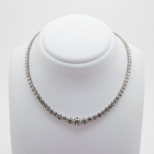 The 18k white gold and diamond rivière necklace features round, brilliant diamonds, evenly distributed along the chain, displayed on a white stand against a simple background. Vintage Jewelry Barcelona
