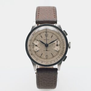 Rellotge de polsera Rolex Chronograph anys 30 amb caixa rodona platejada, esfera crema, dues subesferes, números àrabs negres i corretja de pell marró texturitzada, sobre fons blanc llis. Joieria Vintage Barcelona